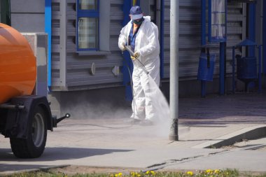 Krakow, Polonya 23.04.2020: Koronavirüs pandemiği sırasında otobüslerin ve tramvayların kirlenmesinden, bakterilerden ve virüslerden arındırılması. Koruyucu giysiler giyen erkekler toplu taşıma araçlarını ve caddeleri antiseptikle yıkıyor
