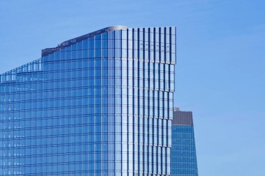 Modern çok katlı ofis gökdeleni mavi gökyüzüne karşı inşa ediyor. Binanın cam cephesi, güneşten parlıyor. Şehrin finans merkezinde birkaç ofis binası var..