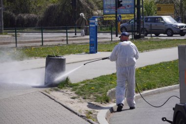 Krakow, Polonya 23.04.2020: Koronavirüs pandemiği sırasında otobüslerin ve tramvayların kirlenmesinden, bakterilerden ve virüslerden arındırılması. Koruyucu giysiler giyen erkekler toplu taşıma araçlarını ve caddeleri antiseptikle yıkıyor