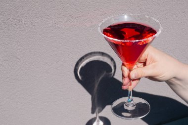 Gri arka planda martini bardağında kırmızı kokteyl. Bardakta kırmızı sıvı. Cam deney şişesi.
