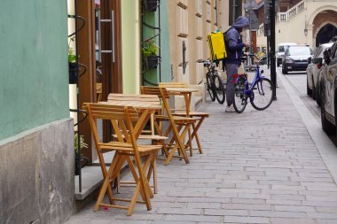 Açık yaz terasları ve kafeler için şehir caddesinde kahve içmek için. Boş ahşap masa ve sandalyeler, koronavirüs yasağı, tecritten sonra tekrar açılma. Açık havada şehir romantizmi. Turizm