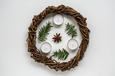 Beyaz arka planda Noel çelengi ya da Paskalya için yuva, mumlar ve ladin dalları. Yaratıcılıkla el işi, çocuklarla dikiş işi. DIY, tatil dekorasyonu. Kopyalama alanı ile düz