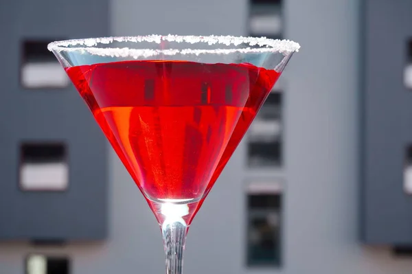 Red cocktail in a Martini glass on a gray background. Red liquid in a glass. Glass beaker