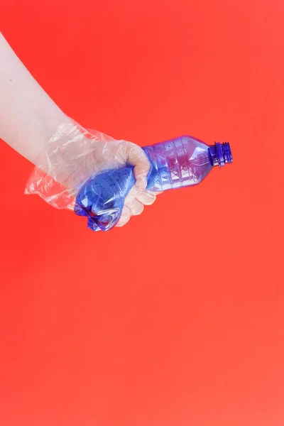 Hand in plastic or rubber disposable glove holds plastic blue bottle of carbonated drink. Zero waste, sorting garbage,reusable containers. ecology environment protection and coronavirus concept.