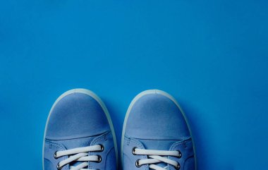 Beyaz bağcıklı açık mavi spor ayakkabılar ve mavi düz arka planda beyaz taban. Uzayı kopyala Yaşam tarzı, yürüyüş için açık hava ayakkabıları. Sıradan uniseks.