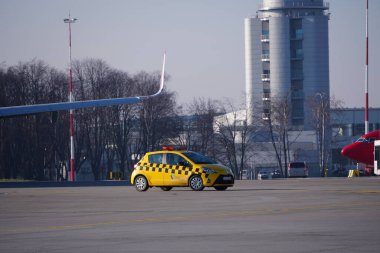 Krakow, Polonya 20.12.2019: Sarı Toyota Yaris havaalanı teknik servis aracı havaalanı pisti boyunca ilerliyor. Pistteki trafik organizasyonu, havaalanı kontrol servisi.