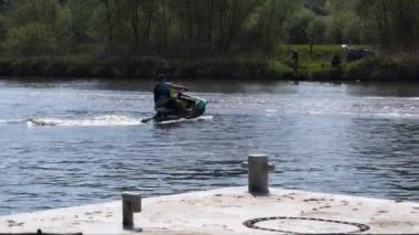 Jet ski 'deki bir adam hızla nehirden geçer, suda dalgalar saçar. Su yüzeyindeki su motorundan gelen dalgalar. Kişisel Su Kaynağı. Krakow, Polonya 09.05.2020