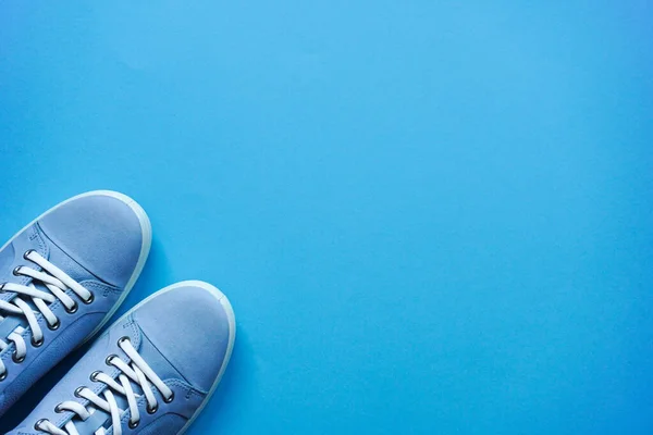 浅蓝色的运动鞋 白色的鞋带和白色的鞋底在蓝色的平坦的背景上 复制空间 生活方式 户外步行鞋 随随便便的异体 — 图库照片