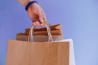 Beyaz kağıt torba ve parlak mor arka planda el işi. Satış sezonu ya da bayram hediyesi olarak alımlar. Noel alışverişi. Çevre dostu paketlerde kurye teslimatı. Kopya alanı.