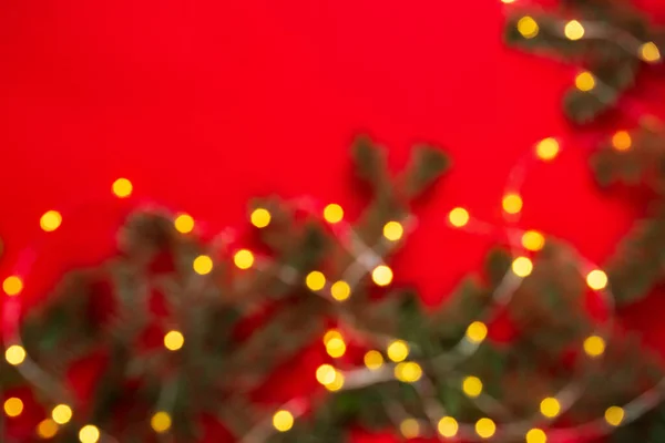 Kırmızı Arka Planda Ladin Dallarında Bulanık Bir Noel Çelengi Yuvarlak — Stok fotoğraf