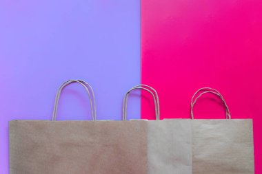 Mor ve pembe arkaplandaki boş kağıt torbaların üst görüntüsü. Kontrastlı arka planda düz konum, sıfır atık. Çöp geri dönüşümü. Tasarımcılar için şablon ya da maket. Plastik kirliliğini durdur