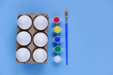 Kırmızı arka planda altı yumurta tepsisi ya da kutusu, çok renkli boya ve fırçalar. Paskalya 'da çocukların yaratıcılığına göre ayarlandı. Asgari paskalya konsepti. Sembol Mutlu Paskalya Düzlüğü