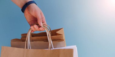 Beyaz kağıt torba ve parlak mor arka planda el işi. Satış sezonu ya da bayram hediyesi olarak alımlar. Noel alışverişi. Çevre dostu paketlerde kurye teslimatı. Kopya alanı.