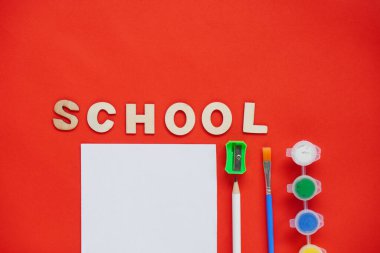 Düz konsept çalış. Eğitim malzemeleri, kalem, fırça, notlar için beyaz kağıt ve kırmızı arka planda boya, okula ya da anaokuluna dönüş. Yaz zamanı, yaratıcılık ve öğrenme geçmişi.