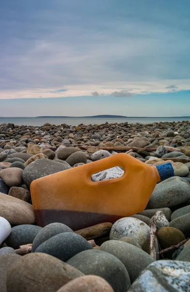 Plastic bottle container with liquid waste washed up on the shore of the west coast of Ireland