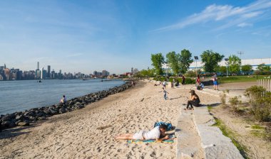 NEW YORK CITY - 2 Ekim 2017: İnsanlar New York 'un Williamsburg tarafındaki East River parkının kumlu kıyısında eğleniyor.