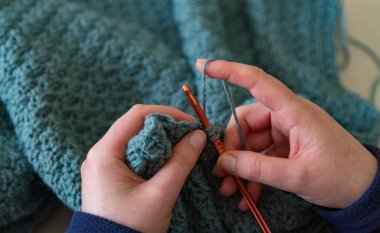 Kadın elleri örgü örer. Kapat ellerini, örgü ören mavi iplik.