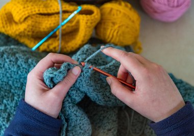 Mavi iplik ören kadının ellerine bakıyorum.