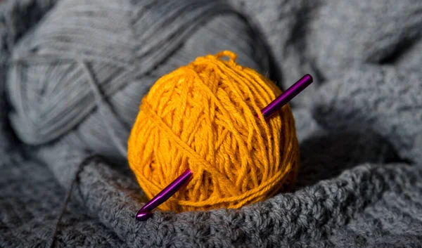 Purple crochet needle stuck in yellow ball of knitting yarn