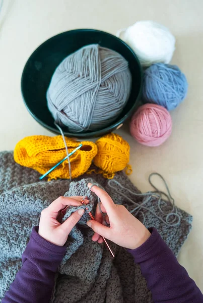 Woman\'s hands crochet background.  Looking down on Woman\'s hands  Crocheting blanket out of light blue yarn