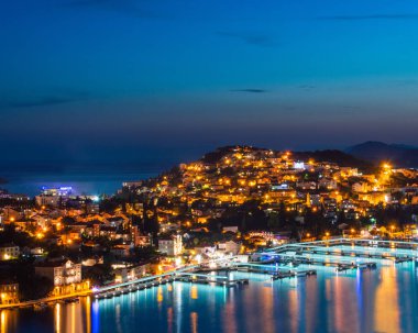 Tepedeki kasabanın gece görüşü. Işıklı güzel deniz manzarası