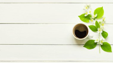 Morning cup of fresh coffee with spring flowers on a white table. Top view with copy space.