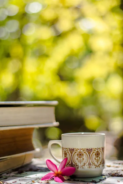 Cup of coffee with flower desk,soft focus background blur book — Stock Photo, Image