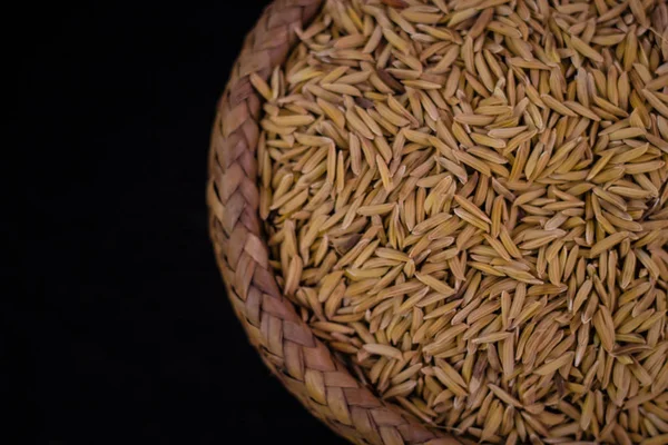 Neloupaná rýže v bambusovém koši s černým pozadím a rozmazané im — Stock fotografie