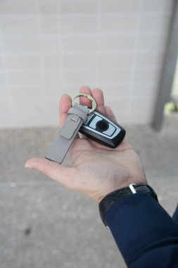 Kablosuz uzaktan kumandalı araba anahtarı ve beyaz arka planda deri zincir.