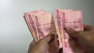 Tayland paralarını sayarken el ele tutuşun. Asyalı kadın 100 baht beyaz arka plan saydı.