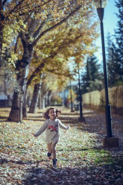 Sonbaharda bir şehir parkında oynayan küçük kız