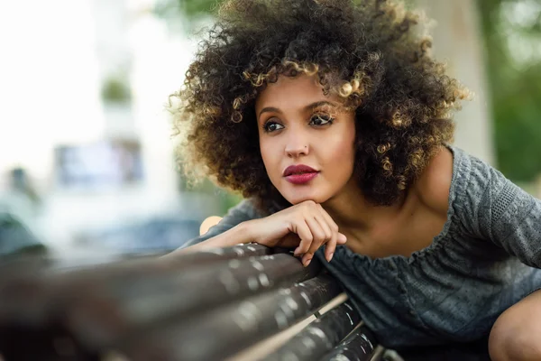 Młody czarny kobieta z fryzura afro, uśmiechając się w miejskich zadumany — Zdjęcie stockowe