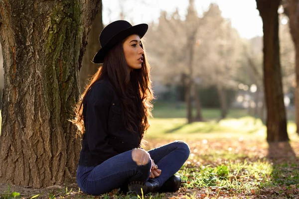 Kobieta siedzi samotnie na zewnątrz kapeluszu — Zdjęcie stockowe