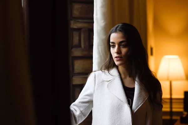 Mooie jonge vrouw die zich voordeed in de buurt van een raam in haar slaapkamer — Stockfoto