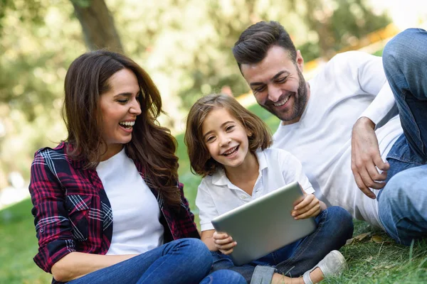 Une famille heureuse dans un parc urbain jouant avec une tablette — Photo