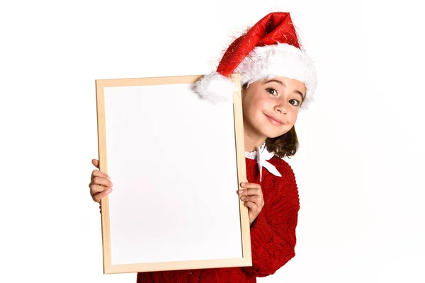 Little girl wearing santa hat holding blank board — Stock Photo, Image