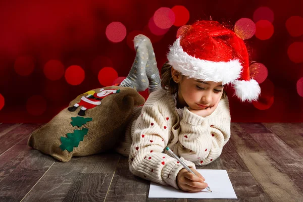 Schattig meisje dragen KERSTMUTS Santa brief schrijven — Stockfoto