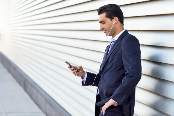 Uomo d'affari che indossa giacca e cravatta blu con uno smartphone . — Foto Stock