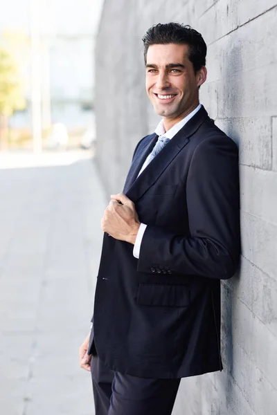 Jovem empresário vestindo terno azul e gravata em fundo urbano — Fotografia de Stock