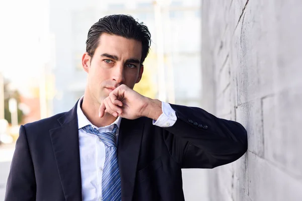 Jovem empresário vestindo terno azul e gravata em fundo urbano — Fotografia de Stock
