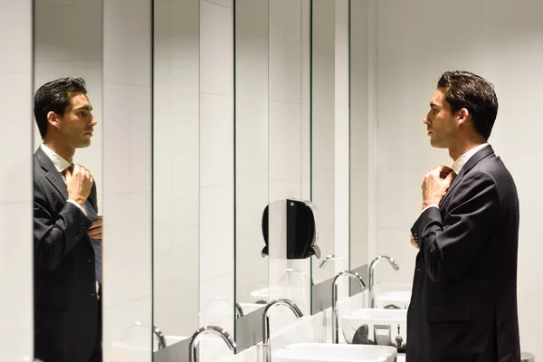 Hombre vistiéndose en un baño público con espejo —  Fotos de Stock