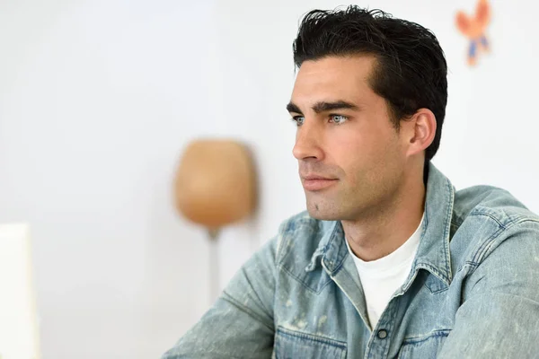 Good looking man wearing denim shirt sitting in a coffee bar