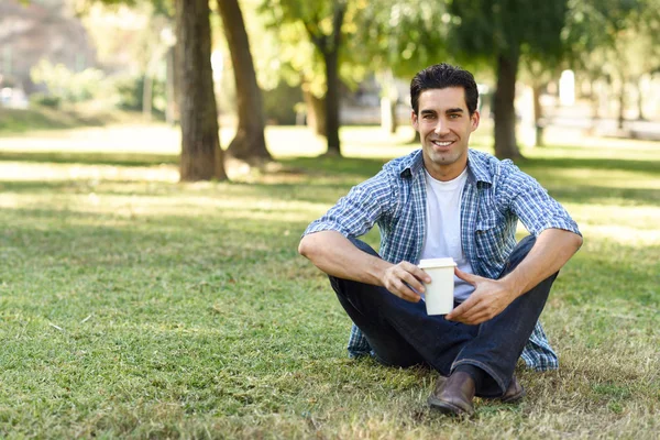 Człowiek pije kawę iść w parku miejskim — Zdjęcie stockowe