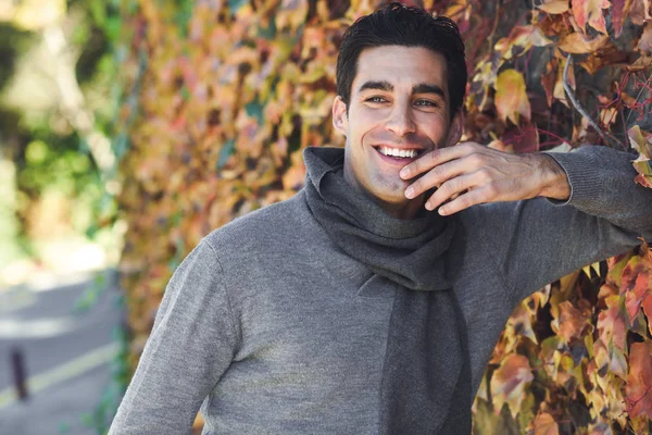 Hombre vistiendo ropa de invierno sonriendo en otoño hojas fondo — Foto de Stock