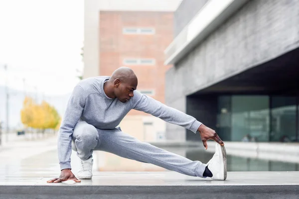 Schwarzer macht Stretching, bevor er im städtischen Hintergrund läuft — Stockfoto