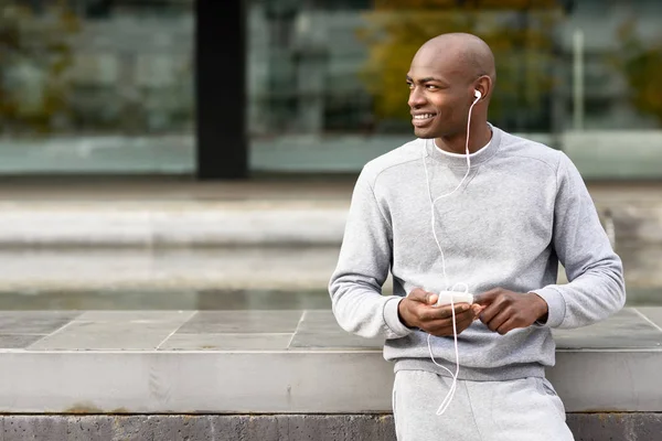 Attraktiver schwarzer Mann hört Musik mit Kopfhörern in der Stadt — Stockfoto