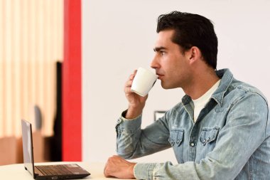 İyi görünümlü bir adam kahve barda oturmuş kot gömlek giymiş