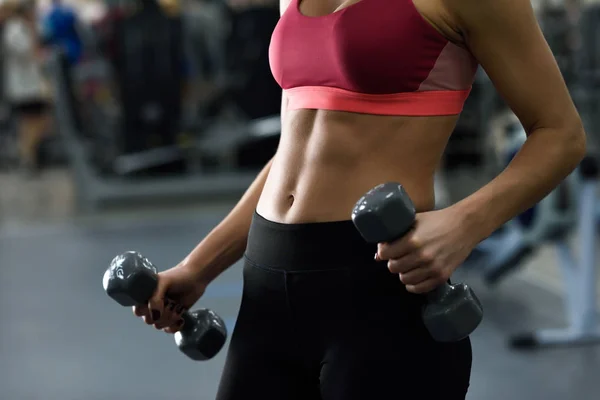 Junge Frau mit schönem Bauch beim Hantelheben im Fitnessstudio — Stockfoto