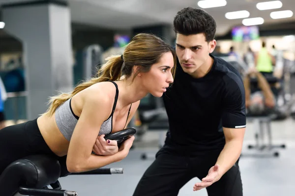 Personal trainer ajudando jovem mulher levantar pesos — Fotografia de Stock