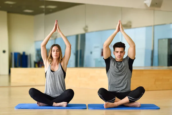 Young woman and man practicing yoga indoors — Stock Photo, Image